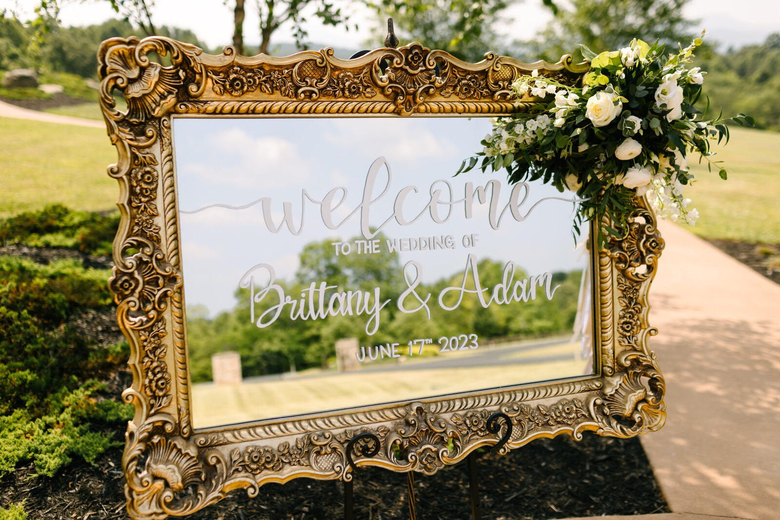 Bloom wedding welcome sign with white lettering and florals